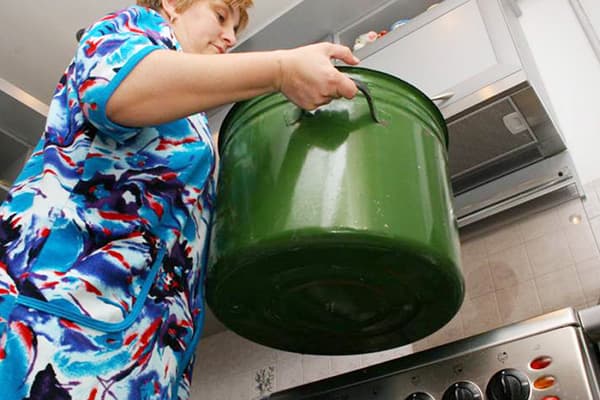 Femme tenant une casserole pour faire bouillir le linge