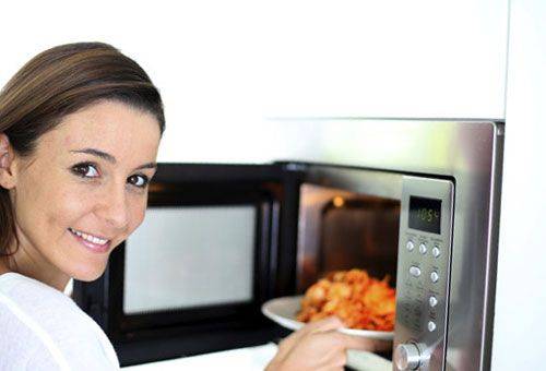 une fille chauffe des aliments au micro-ondes