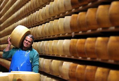 Un homme dans un entrepôt porte une meule de fromage