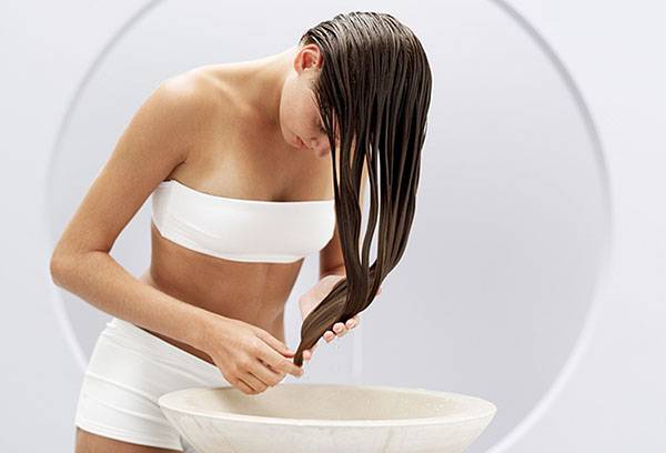 Une fille se lave les cheveux dans une décoction d'herbes