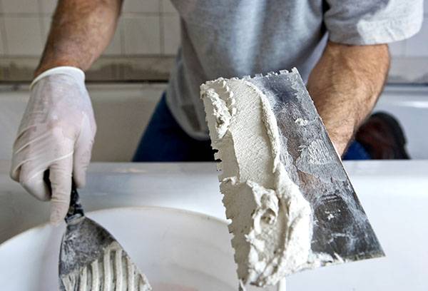 Application de colle à plâtre sur une truelle crantée