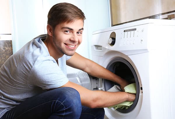 Un homme sort du linge de la machine à laver