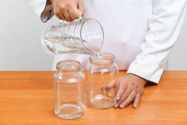 Homme versant de l'eau dans des bocaux