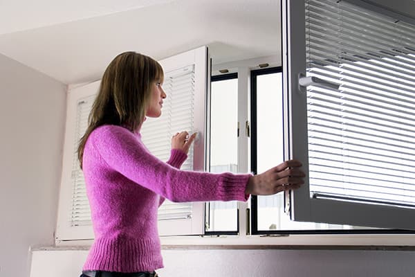 La fille ouvre la fenêtre pour la ventilation