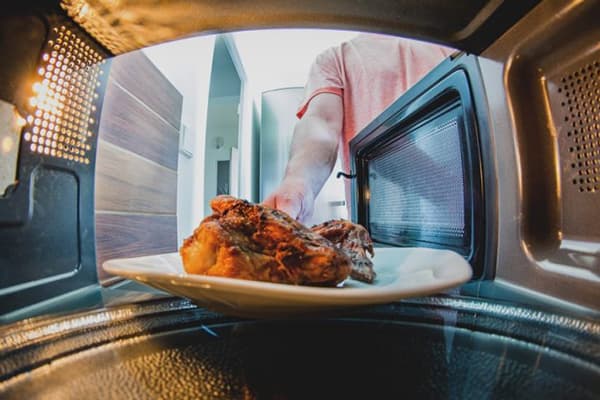 Un homme met de la viande au micro-ondes