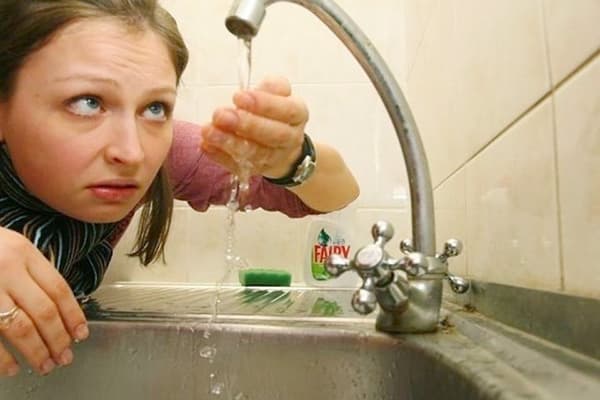 Femme regardant l'eau du robinet