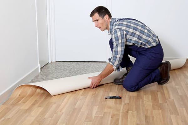 Un homme pose du nouveau linoléum sur du vieux