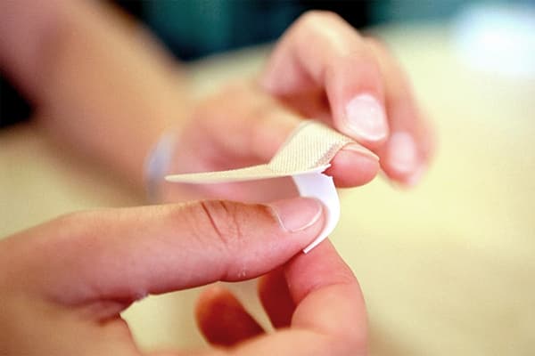 Une fille se couvre le doigt avec un pansement