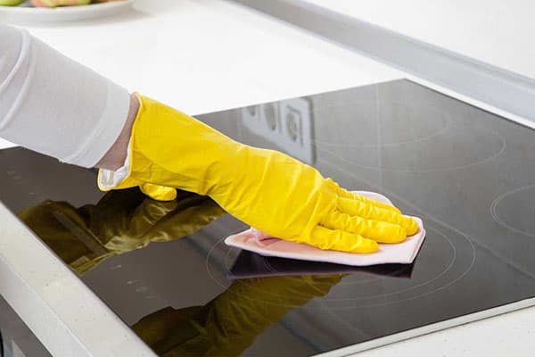 La ménagère essuie la plaque de cuisson avec une serviette