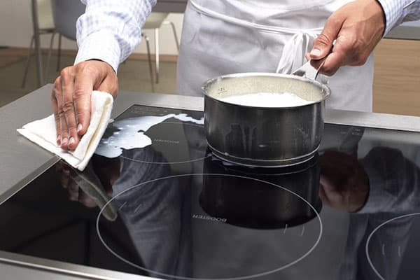 Le chef essuie le lait renversé sur la cuisinière à induction