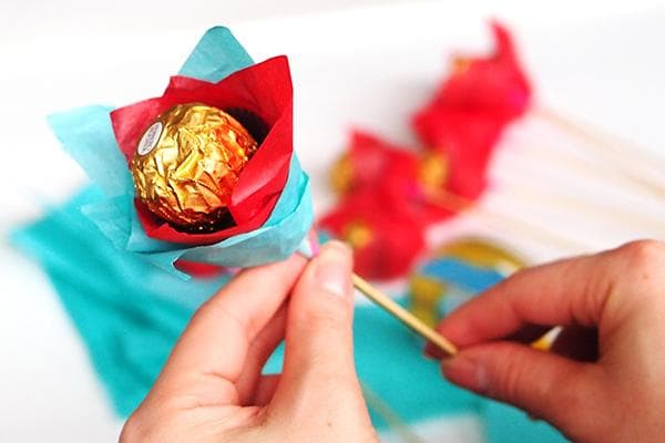 Une femme fabrique une fleur à partir de bonbons, de brochettes et de papier