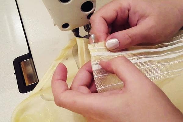 Femme ourlant des rideaux