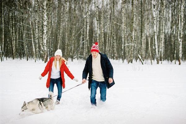 Couple marchant avec un chien en hiver