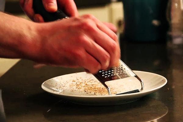 Un homme frotte la muscade sur une râpe