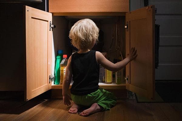 Enfant devant une armoire contenant des produits chimiques ménagers