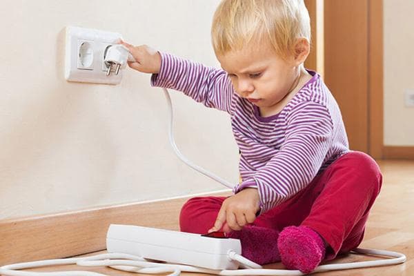 Un enfant insère la fiche d'un parasurtenseur dans une prise