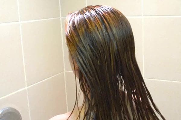 La jeune fille a appliqué de l'huile sur ses cheveux