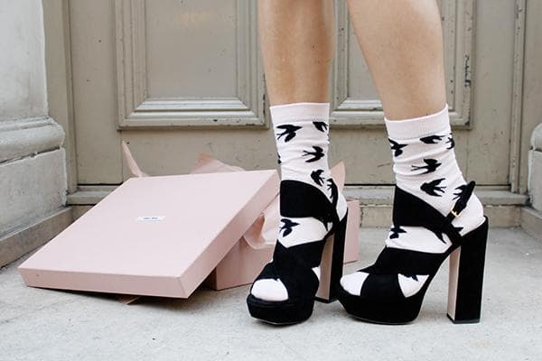 Une fille étire ses sandales en daim en les mettant sur ses chaussettes