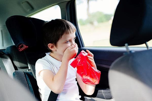 Un enfant vomit dans une voiture