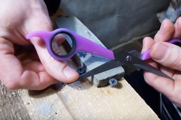 Aiguiser les ciseaux sur une pierre à aiguiser