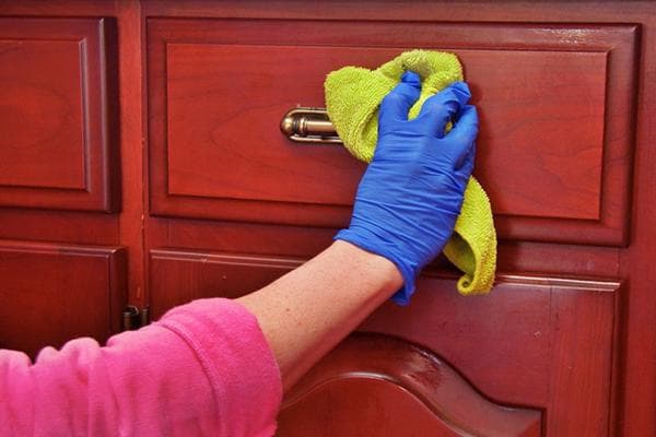 Femme essuyant les meubles avec un chiffon humide