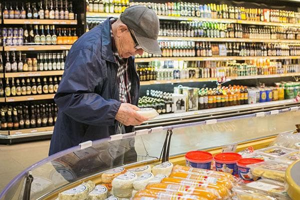 Un homme choisit du fromage dans un hypermarché