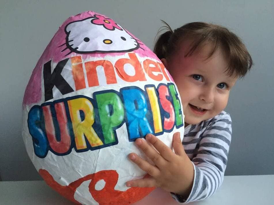 Enfant avec une surprise Kinder géante en papier mâché