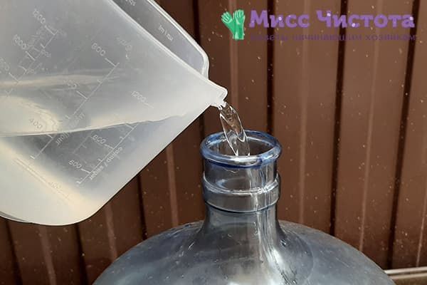 Verser une solution de soude dans une bouteille de 19 litres