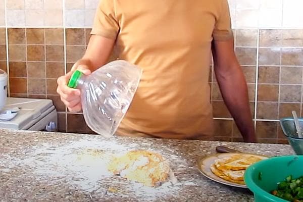 Un homme recouvre la pâte avec le dessus d'une aubergine en plastique.