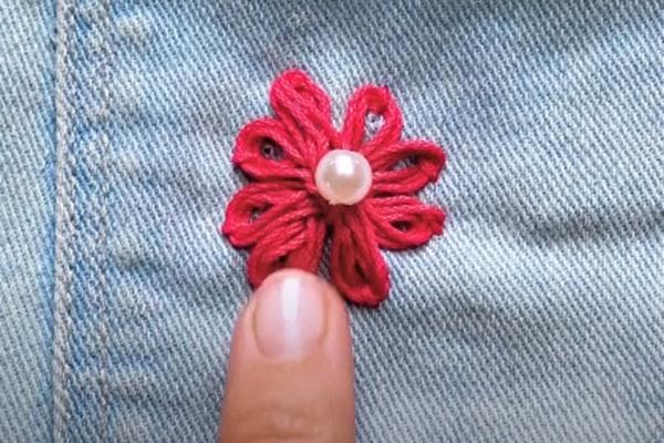 Fleur brodée sur un jean avec des fils épais