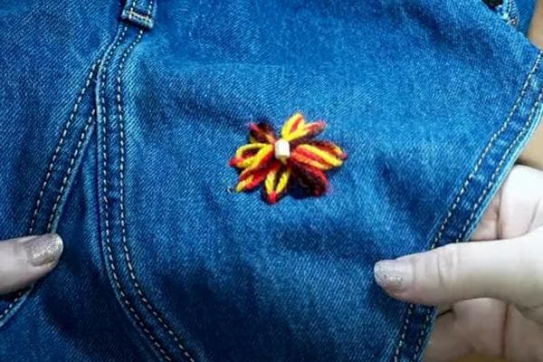 Une fleur à la place d'un trou dans un jean