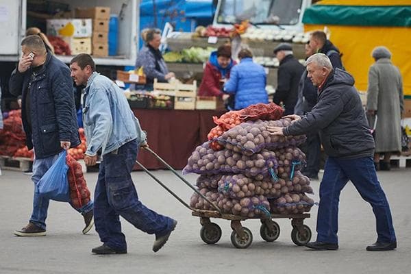 Hommes transportant des pommes de terre dans des sacs