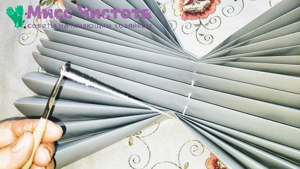 on passe la dentelle à travers les fentes des stores en papier vierges