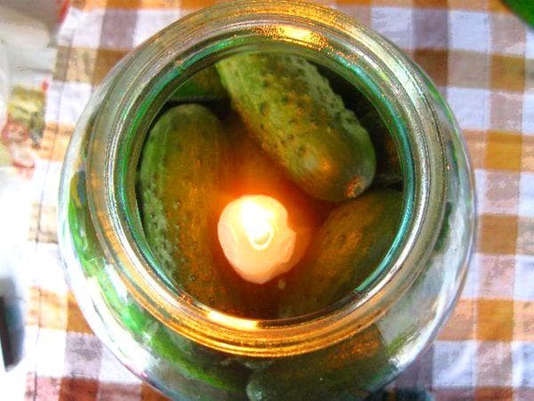 Concombres frais dans un pot avec une bougie
